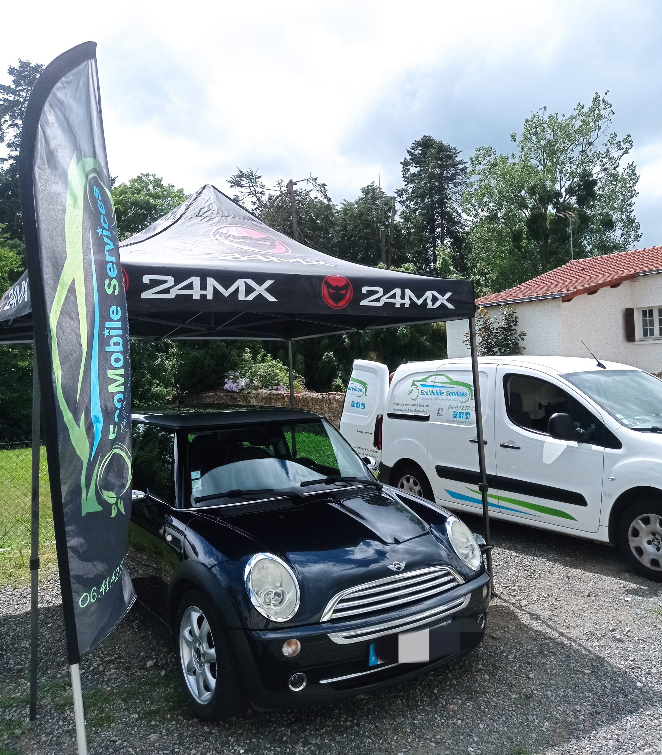 Stand promotionnel pour services de nettoyage de voiture avec mini cooper noire et van de l'entreprise Ecomobile garés devant