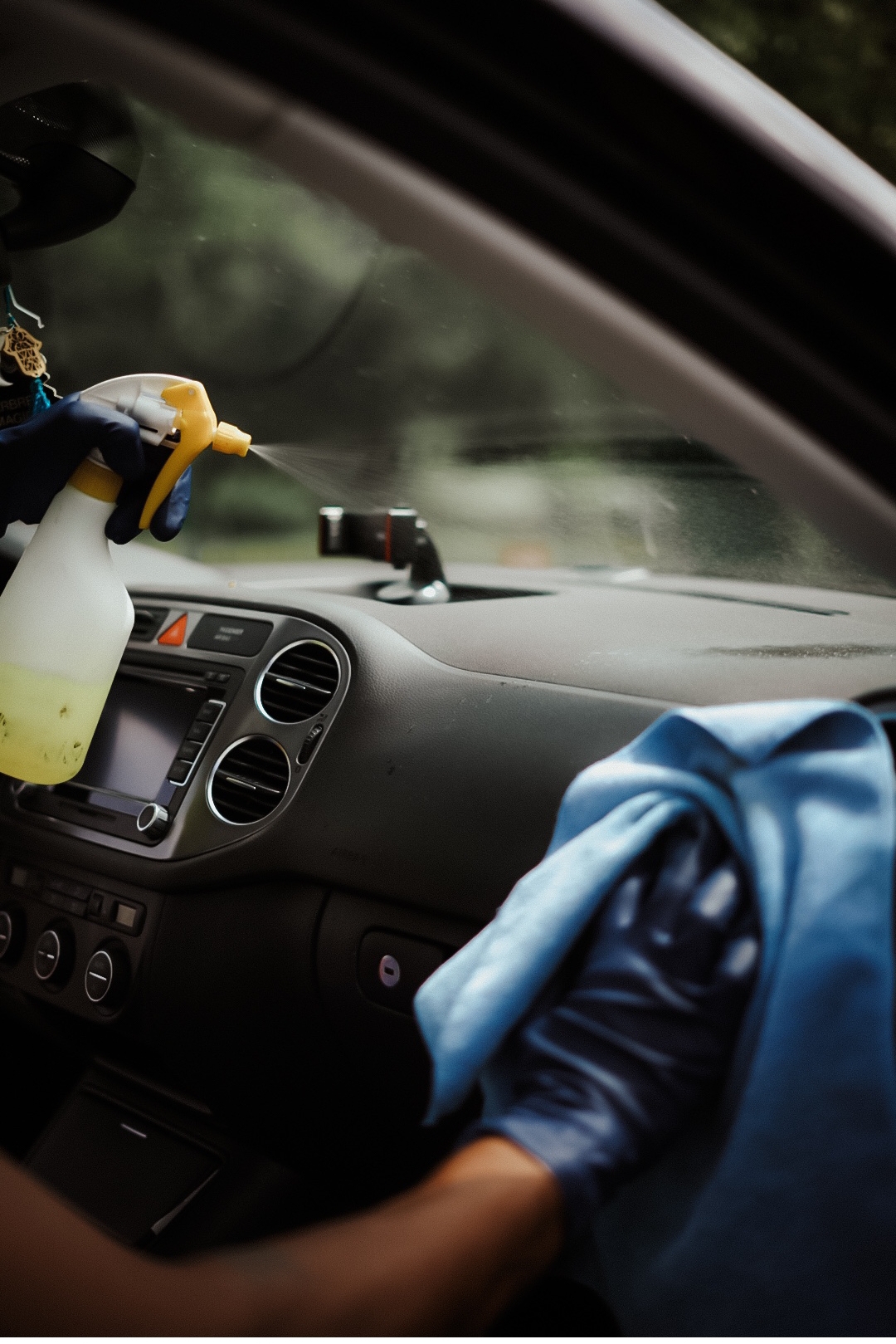 Nettoyage minutieux du tableau de bord d'une voiture avec chiffon et spray nettoyant par un professionnel du detailing automobile Ecomobile